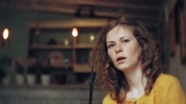 Genç bir kadın bir kafe barda bir kokteyl içiyor ve bir telefon kullanır