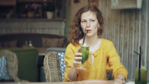 Jonge vrouw drinken een cocktail in een café-bar — Stockvideo