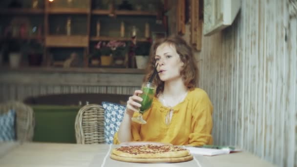 Mujer joven bebe un cóctel en un bar cafetería — Vídeo de stock