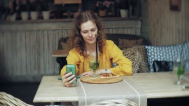 Genç kadın bir kafe barda bir smartphone cep telefonu ile bir pasta lazım