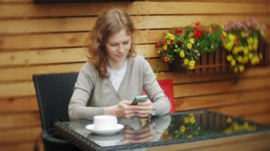 Genç kadın bir tablet ve telefon kullanıyorsa, bir kafe barda çay içer