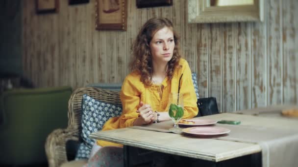 Une jeune femme boit un cocktail dans un café-bar — Video