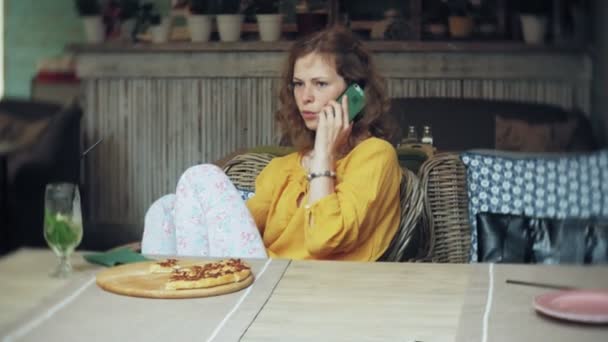 Een jonge vrouw een cocktail drinken in een café-bar en maakt gebruik van een telefoon — Stockvideo