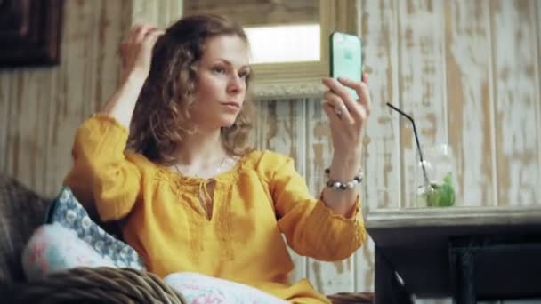 En ung kvinna dricker en cocktail på en cafébar och använder en telefon — Stockvideo