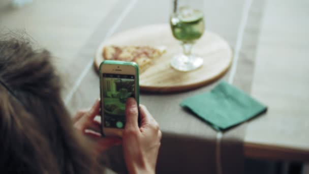 Ung kvinna tar en paj i en cafébar på en smartphone — Stockvideo