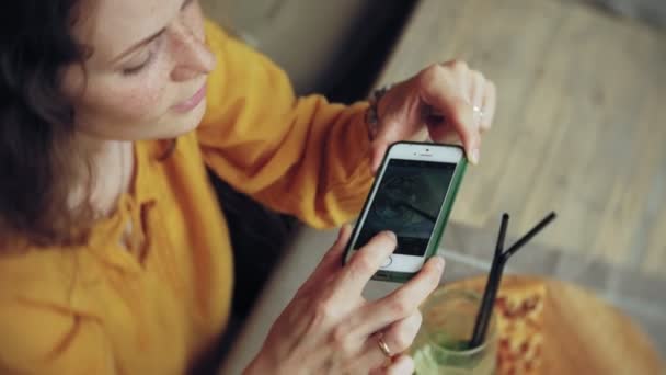 Jovem pega uma torta em um bar de café em um smartphone — Vídeo de Stock