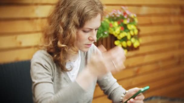 O tânără folosește o tabletă și un telefon, bea ceai într-un bar de cafenele — Videoclip de stoc