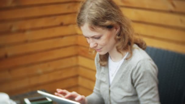 Genç kadın bir tablet ve telefon kullanıyorsa, bir kafe barda çay içer — Stok video
