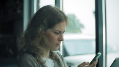 Genç kadın bir tablet ve telefon kullanıyorsa, bir kafe barda çay içer