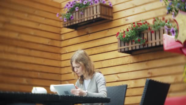 年轻妇女使用片剂和电话, 喝茶在咖啡馆酒吧 — 图库视频影像