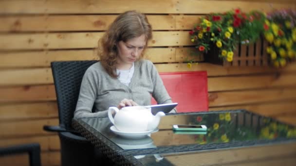 Mujer joven disfruta de una tableta en un bar cafetería — Vídeo de stock