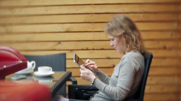 Mujer joven disfruta de una tableta en un bar cafetería — Vídeos de Stock