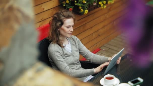 Jovem mulher gosta de um tablet em um bar de café — Vídeo de Stock