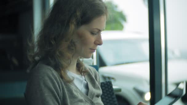 Giovane donna utilizza un tablet e telefono, beve il tè in un bar — Video Stock