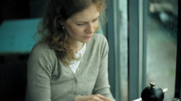 Mladá žena používá tablet a telefon, pije čaj v café bar — Stock video
