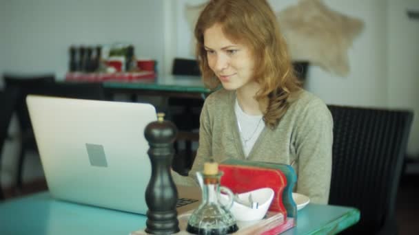Joven mujer de negocios hermosa sentada en el sofá en la mesa con la tableta y mirando a través de papel — Vídeo de stock