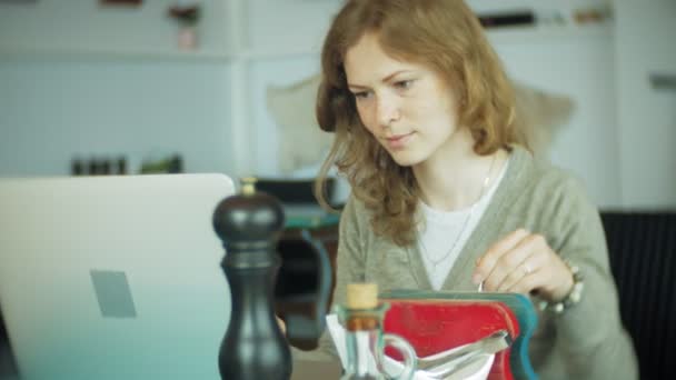 Jonge mooie zakenvrouw zittend op de Bank aan tafel met tablet en op zoek via papier — Stockvideo