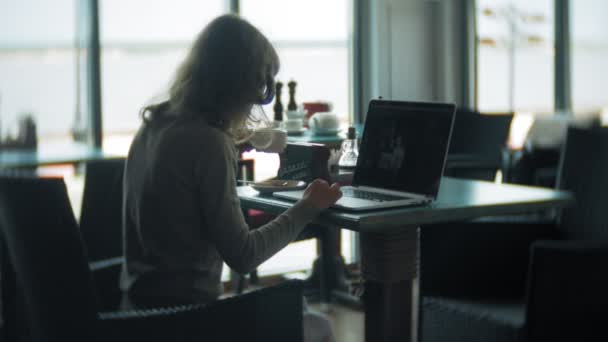 Joven mujer de negocios hermosa sentada en el sofá en la mesa con la tableta y mirando a través de papel — Vídeos de Stock