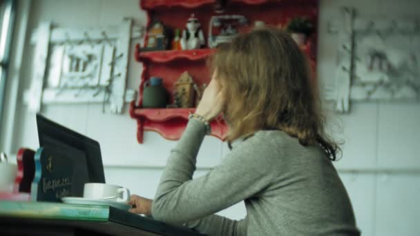 Junge schöne Geschäftsfrau sitzt auf Sofa am Tisch mit Tablet und blättert durch Papier — Stockvideo
