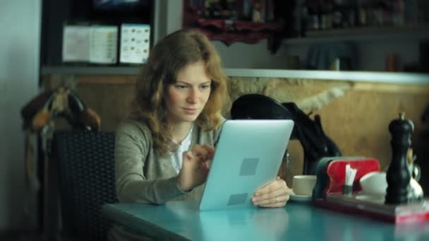 Jonge vrouw geniet van een tablet in een café-bar — Stockvideo