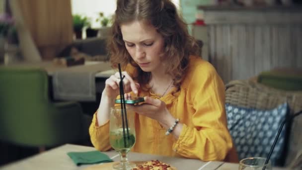 Mujer joven toma un pastel en un bar cafetería en un teléfono inteligente — Vídeo de stock