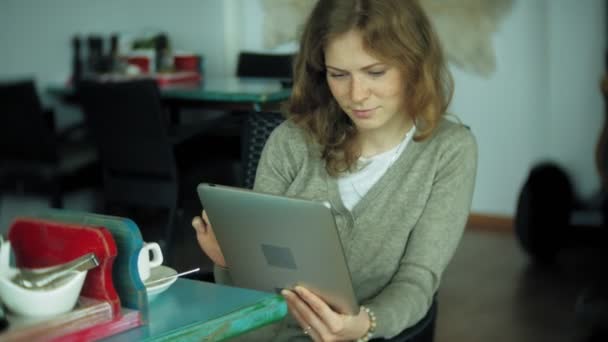 Jonge vrouw geniet van een tablet in een café-bar — Stockvideo