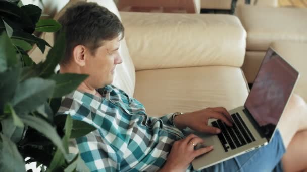Biznes człowiek siedzi na kanapie przy stole z tabletu i patrząc przez papier — Wideo stockowe