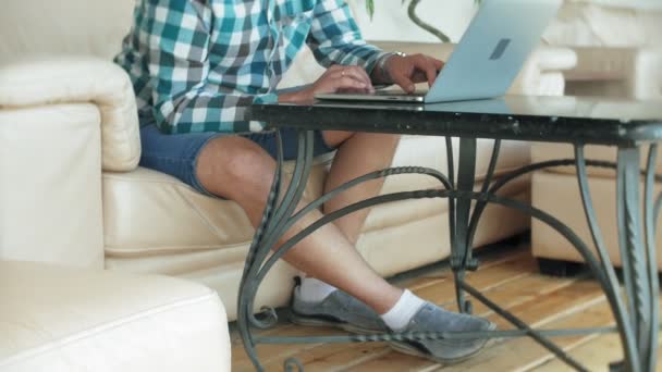 Ділова людина сидить на дивані за столом з планшетом і дивиться через папір — стокове відео