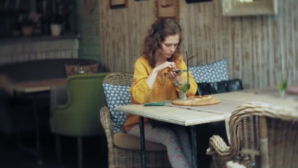 Mujer joven toma un pastel en un bar cafetería en un teléfono inteligente — Vídeo de stock