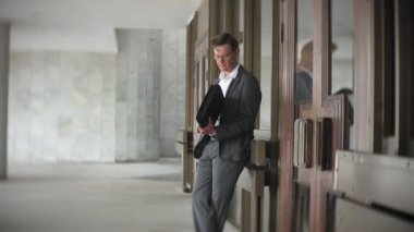bir ofis binası için gönderilen bir genç, saygın bir iş adamı. Onun elinde tutan bir evrak çantası, belgeler üzerinden görünüyor.