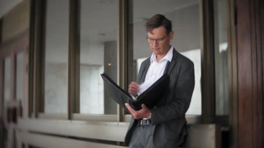 bir ofis binası için gönderilen bir genç, saygın bir iş adamı. Onun elinde tutan bir evrak çantası, belgeler üzerinden görünüyor.