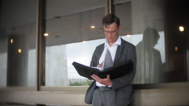 bir ofis binası için gönderilen bir genç, saygın bir iş adamı. Onun elinde tutan bir evrak çantası, belgeler üzerinden görünüyor.