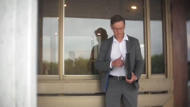 Een jonge, respectabele zakenman verzonden naar een kantoorgebouw. In zijn handen hij bezit van een aktetas, ziet er door middel van documenten. — Stockvideo