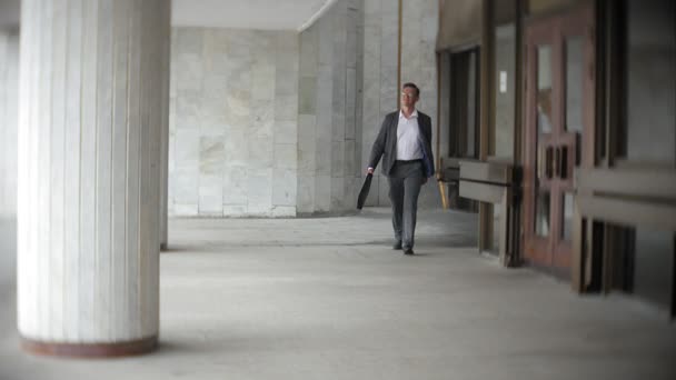 Empresario llevando maletín mientras avanza. Hombre en ropa formal caminando cerca del moderno edificio de oficinas, longitud completa, espacio para copias. Concepto de negocio y éxito — Vídeos de Stock