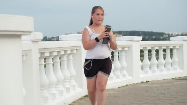 Νέοι λίπος κορίτσι τρέχει, ρίχνοντας το βάρος, να ακούτε μουσική με ακουστικά έννοια του υγιεινού τρόπου ζωής — Αρχείο Βίντεο