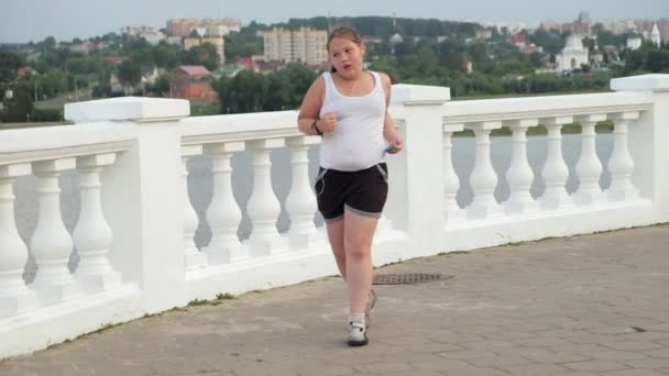 Young fat girl running, shedding weight, listening to music in headphones concept of healthy lifestyle — Stock Video