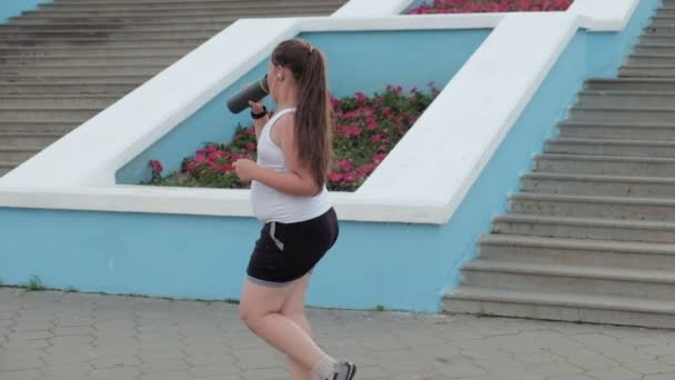 Niña gorda corriendo escaleras abajo, perdiendo peso, escuchando música en los auriculares concepto de estilo de vida saludable super cámara lenta — Vídeo de stock