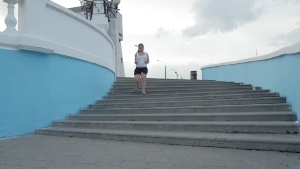 Young fat girl running down stairs, shedding weight, listening to music in headphones concept of healthy lifestyle super slow motion — Stock Video