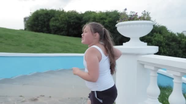 Niña gorda corriendo escaleras abajo, perdiendo peso, escuchando música en los auriculares concepto de estilo de vida saludable super cámara lenta — Vídeos de Stock