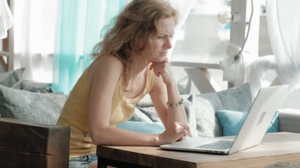 Jeune femme d'affaires assise à table et prenant des notes dans un notebook.On table est ordinateur portable, smartphone. Apprentissage étudiant en ligne. Blogueur . — Video