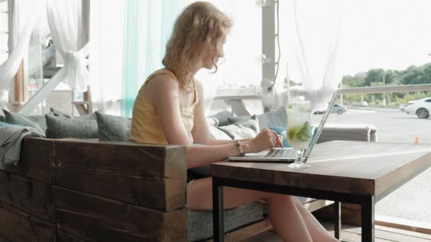 若いビジネス女性飲みモヒート カクテル リビング テーブルで、ノートでメモを取るします。ノート パソコン、スマート フォンです。オンライン教育の学生。ブロガー. — ストック動画