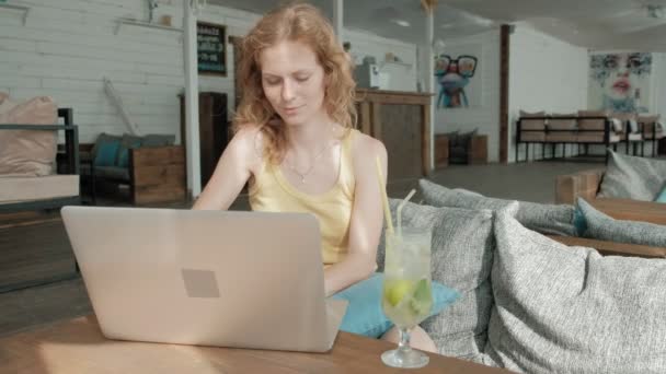 Jovem mulher de negócios bebendo coquetel mojito sentado à mesa e tomando notas em notebook.On é um laptop, smartphone. Ensinar alunos online. Blogueiro . — Vídeo de Stock