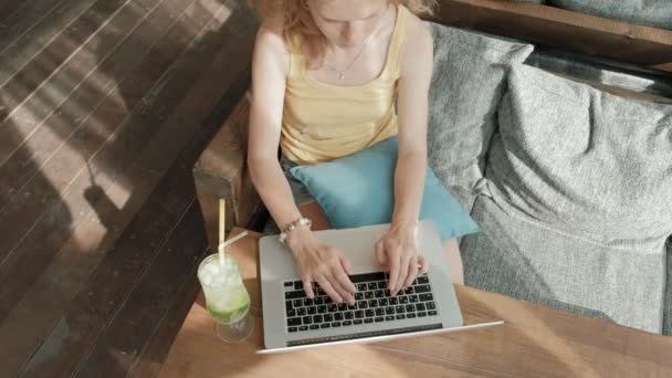 Joven mujer de negocios bebiendo cóctel mojito sentada en la mesa y tomando notas en el cuaderno. Enseñando a los estudiantes en línea. Blogger . — Vídeo de stock