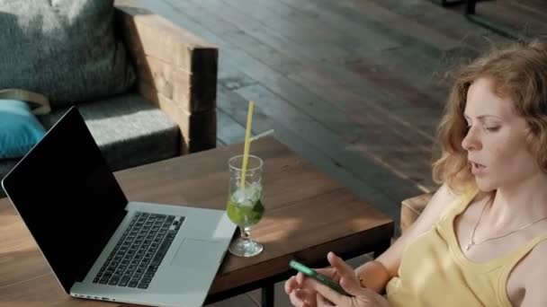 Giovane donna d'affari bere cocktail di mojito seduto a tavola e prendere appunti nel notebook. Insegnare agli studenti online. Blogger . — Video Stock