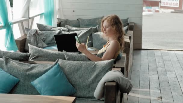 Jeune femme d'affaires boire cocktail mojito assis à table et prendre des notes dans le notebook.On est un ordinateur portable, smartphone. Enseigner aux étudiants en ligne. Blogueur . — Video