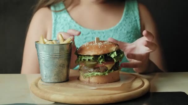 Dik meisje gretig eten van een hamburger, concept van een gezond dieet — Stockvideo
