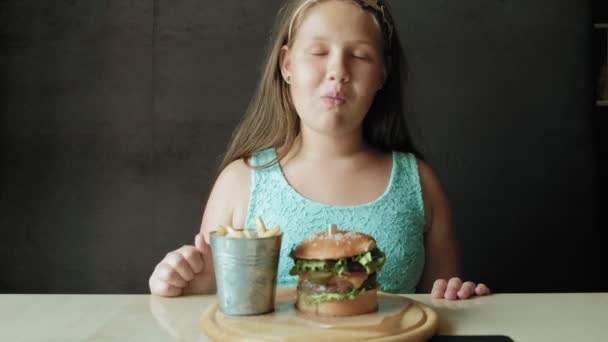 Dicke Mädchen essen eifrig einen Hamburger, Konzept einer gesunden Ernährung — Stockvideo