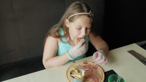 Dik meisje gretig eten van een hamburger, concept van een gezond dieet — Stockvideo