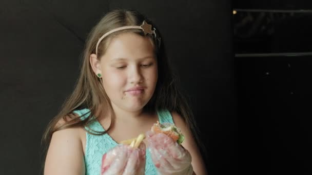 Fett flicka ivrigt äter en hamburgare, begreppet en hälsosam kost — Stockvideo