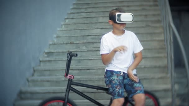 De jongen zit op de ladder in virtuele bril, naast de fiets, Bmx — Stockvideo